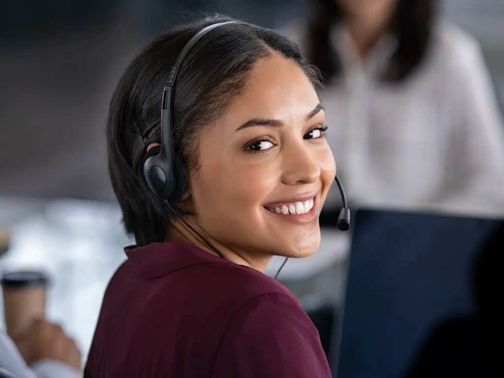 Atendente de telemarketing com fone de ouvido analisando dados em um computador